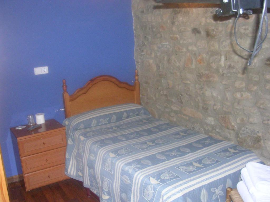 Dormitorio pequeño con cama y pared de piedra en Apartamentos Turisticos Sol y Nieve, en Jaca
