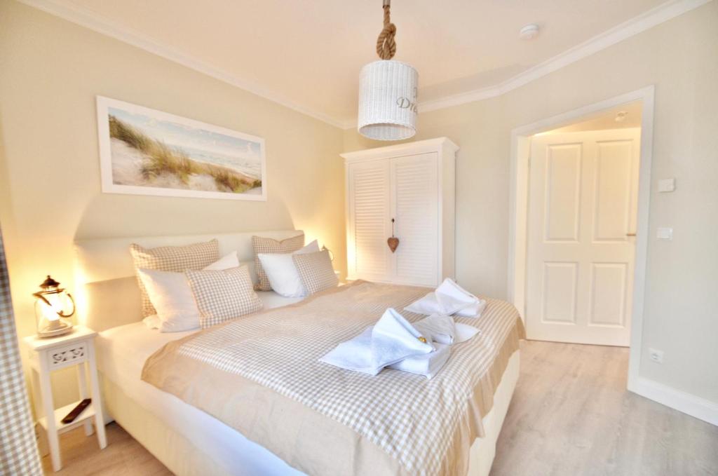 um quarto com uma cama grande e lençóis brancos em Villa Strandblick 9 em Zingst