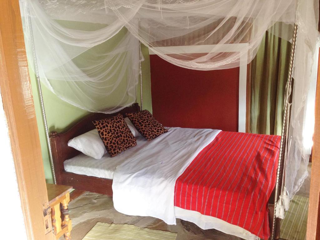 a bedroom with a canopy bed with red and white at Maasai Simba Camp in Amboseli