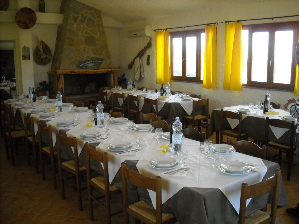 a room filled with tables and chairs with white tablecloths at Agriturismo Depalmas in Stintino