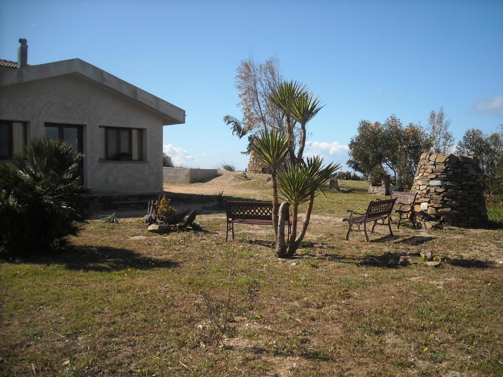 two benches in a yard next to a house at Agriturismo Depalmas in Stintino
