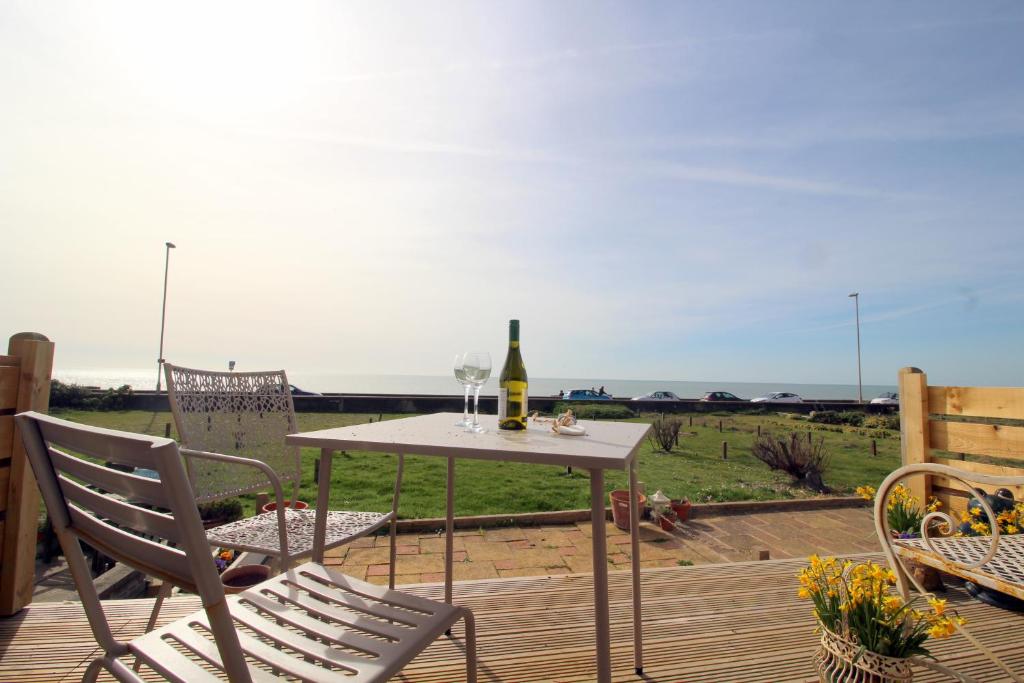 a table with two glasses of wine on a deck at Pebbles Beach House By Air Premier in Seaford