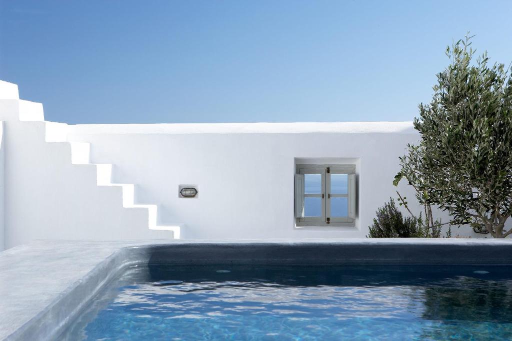 a swimming pool in front of a white house at Villa Fabrica Santorini in Pyrgos