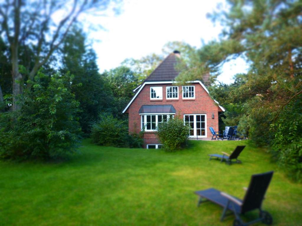 een rood bakstenen huis met twee stoelen in de tuin bij Ferienwohnung Bi Elschen in Nebel