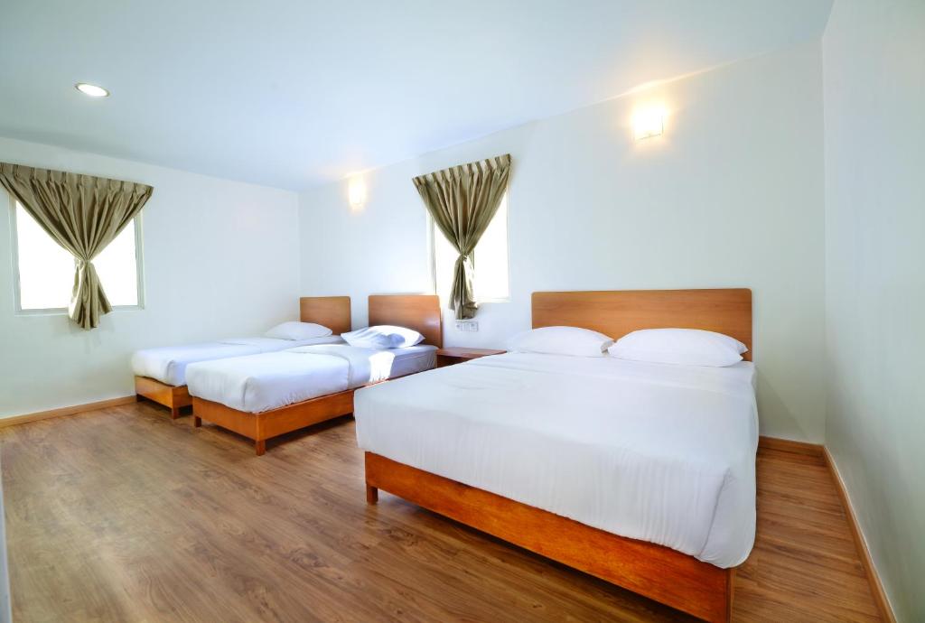 two beds in a room with wooden floors at MG Hotel in Mersing