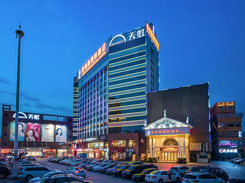 a large building with cars parked in a parking lot at Venus International Hotel Shenzhen Gongming Tianhong in Xitian