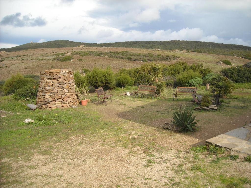 two benches and a stone structure in a field at Agriturismo Depalmas in Stintino