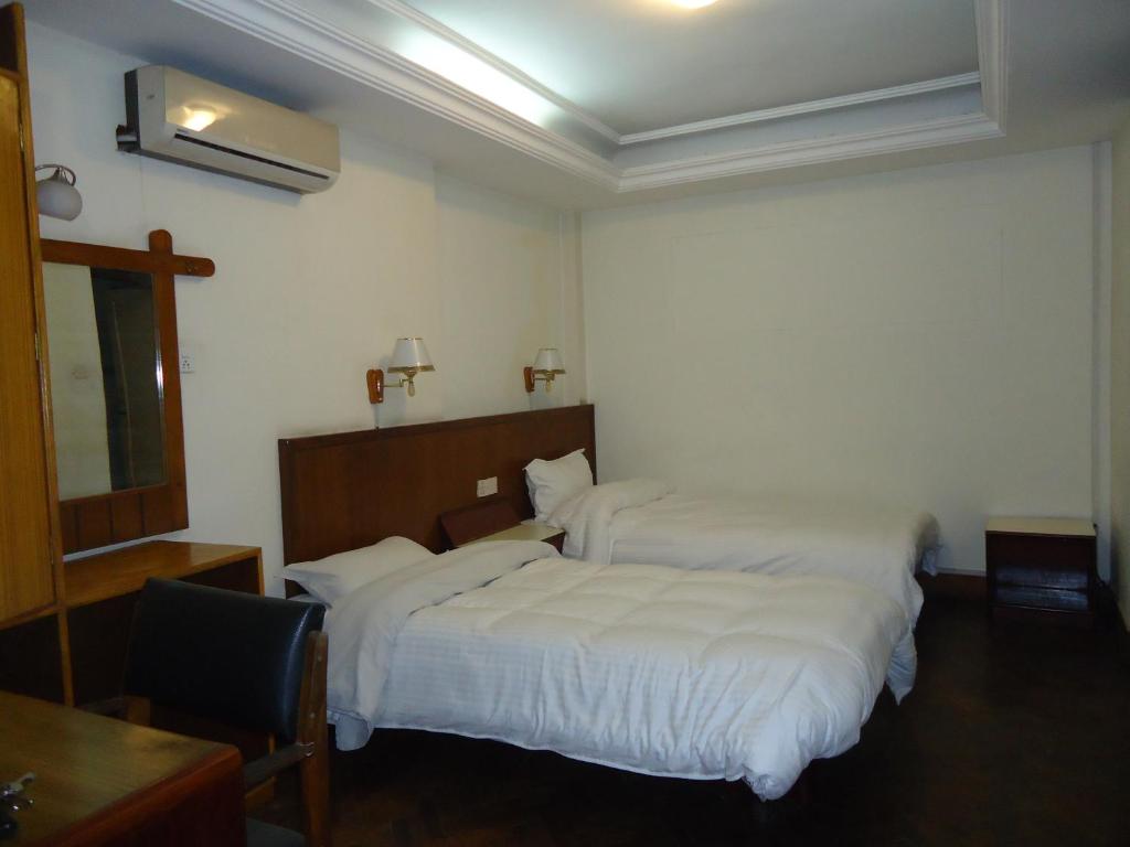 a bedroom with two beds with white sheets at Hotel Earth House in Kathmandu