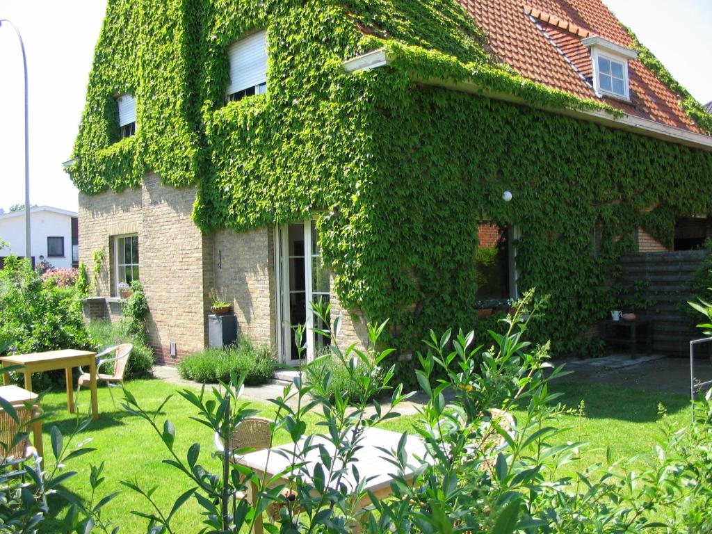 a building covered in ivy with a table and chairs at B&B Villa Vanilla in Ieper