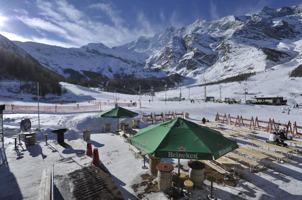 a snow covered ski slope with a green umbrella at Hotel THE LARIX ski-in ski-out in Saas-Fee