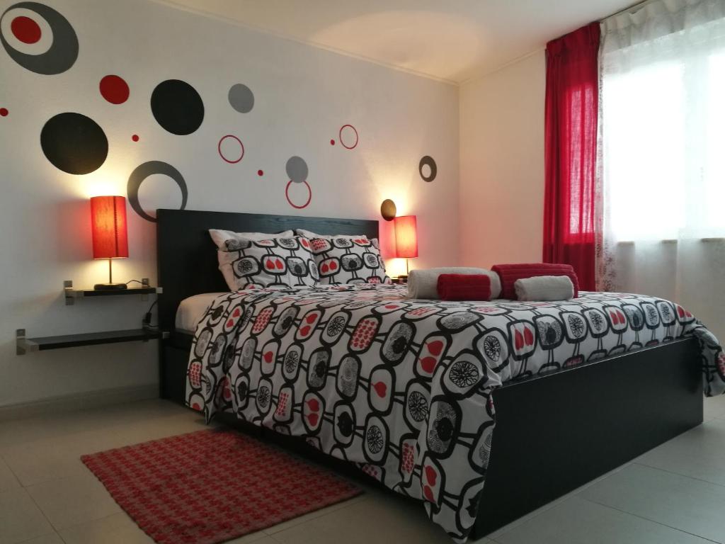 a bedroom with a bed with a black and red comforter at Apartamentos Costa in Costa da Caparica