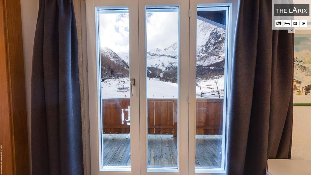 a window with a view of a snowy mountain at Hotel THE LARIX ski-in ski-out in Saas-Fee