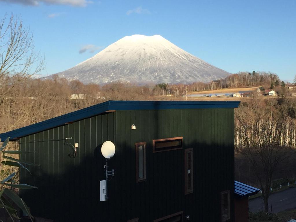 a building with a snow covered mountain in the background at Niseko Nikuyadoya in Niseko