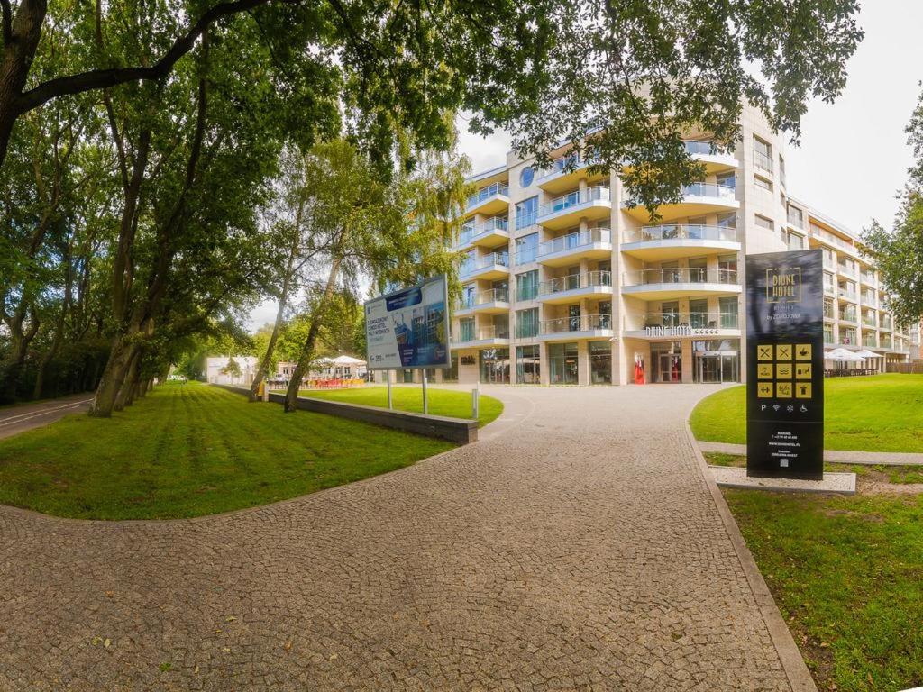 a building with a sign in front of a park at Diune Apartment in Kołobrzeg