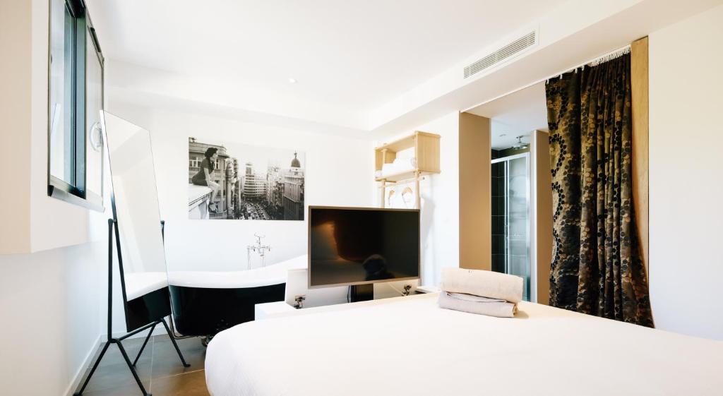 a bedroom with a white bed and a television at Citta di Lume Suites &amp; Lofts in Porto-Vecchio