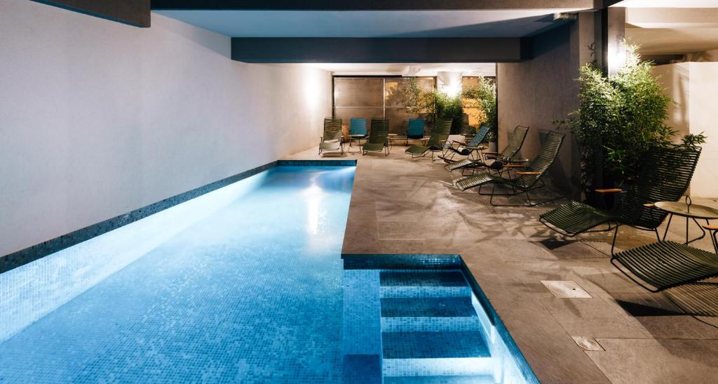 a swimming pool in a building with chairs and tables at Citta di Lume Suites & Lofts in Porto-Vecchio
