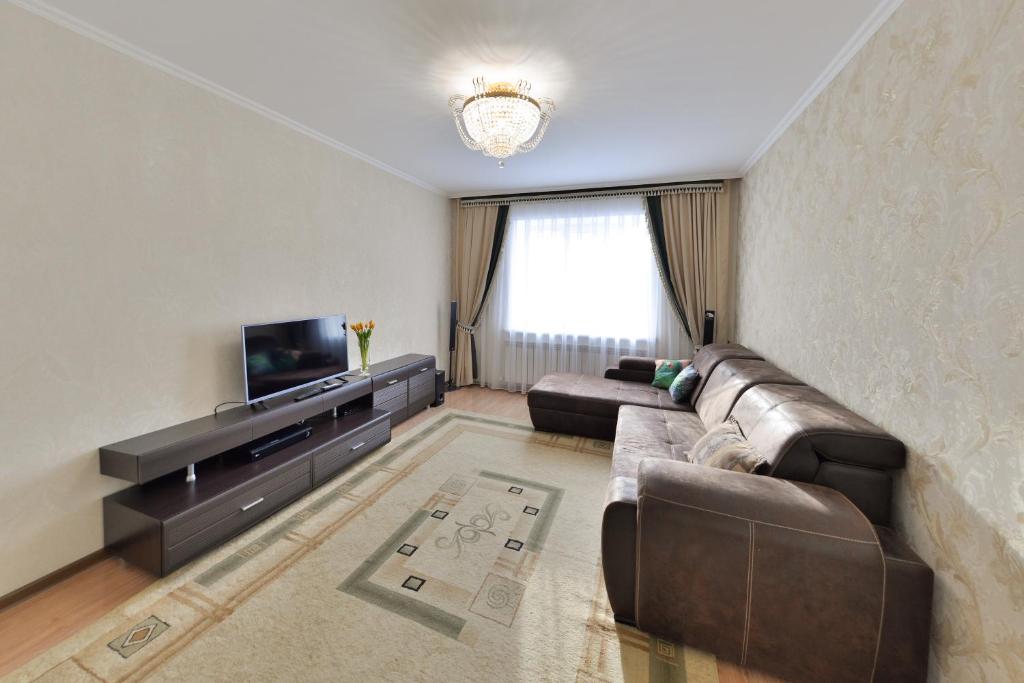 a living room with a couch and a television at Akbulak Town Lux in Astana