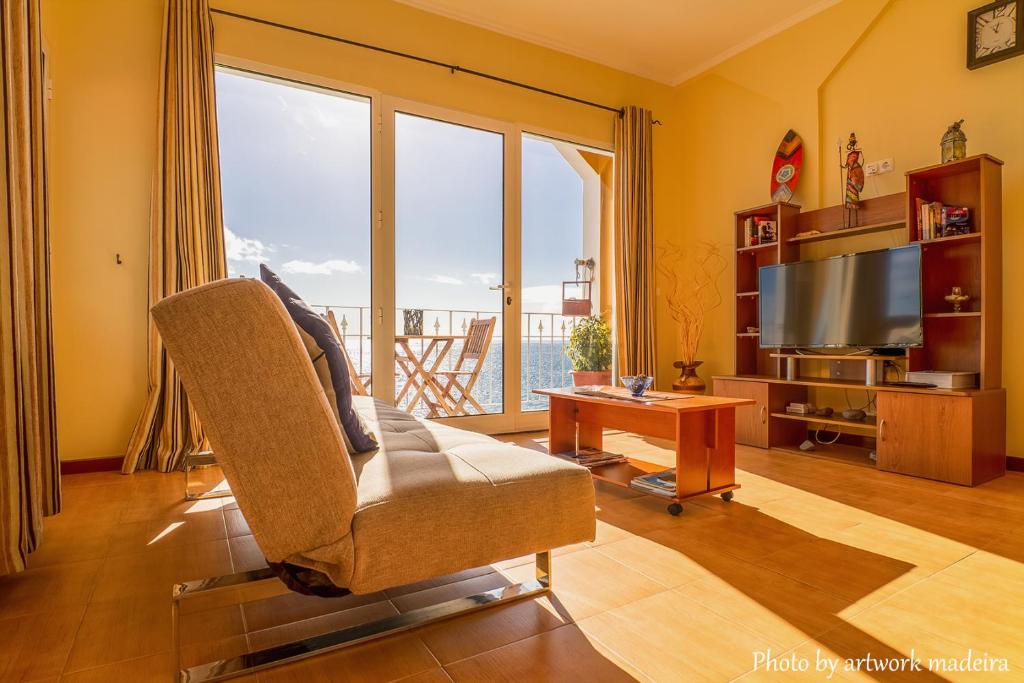 One Love Maktub في بول دو مار: غرفة معيشة فيها تلفزيون وكرسي وطاولة