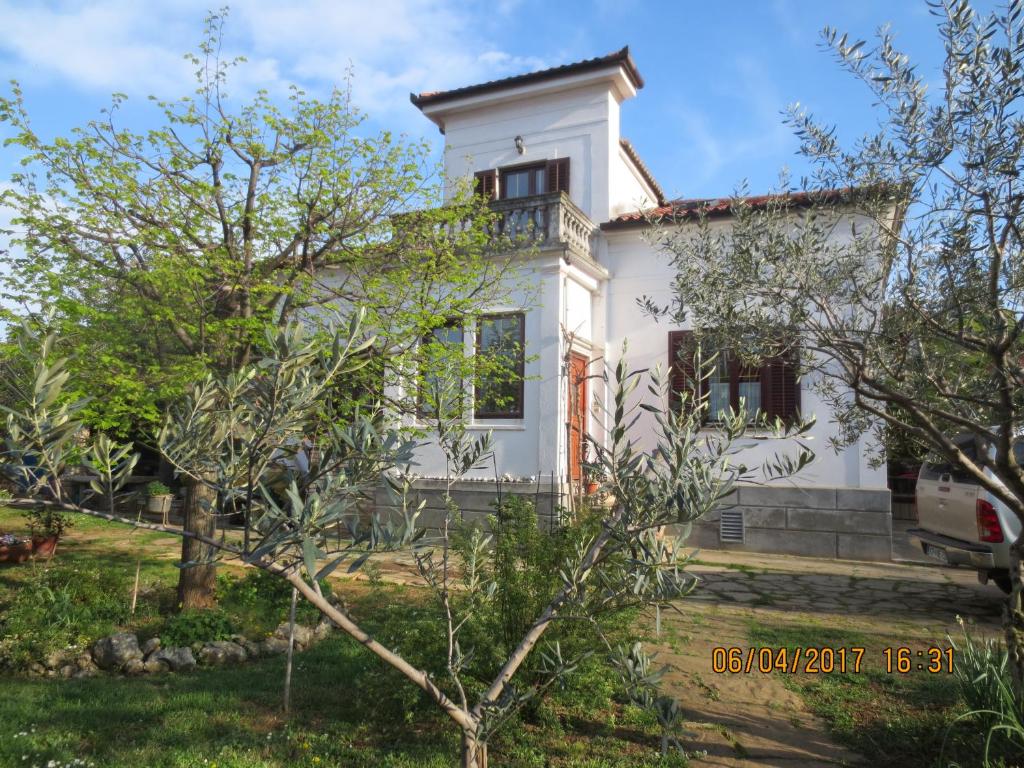 ein weißes Haus mit Bäumen davor in der Unterkunft Apartments Vila Marija in Izola