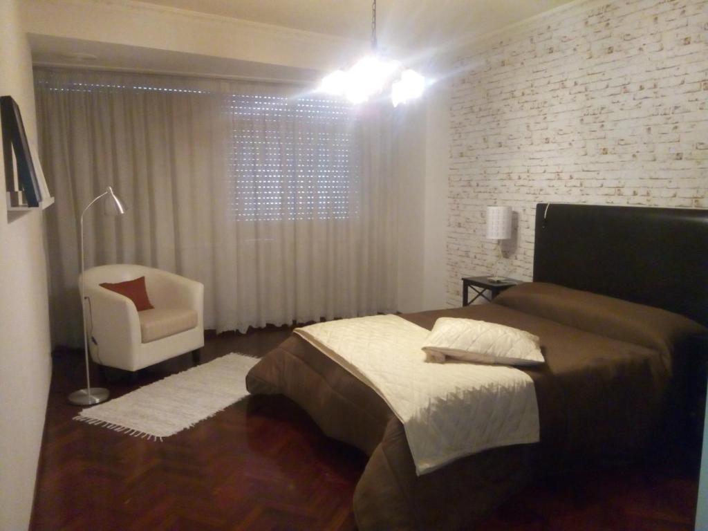 a bedroom with a bed and a chair in it at Piso Bergantiños in Carballo