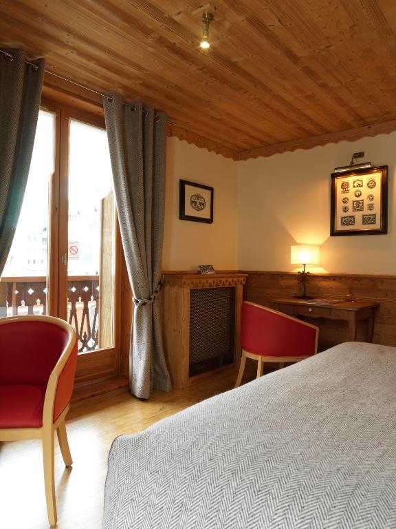 a bedroom with a bed and a desk and a window at Auberge du Manoir in Chamonix