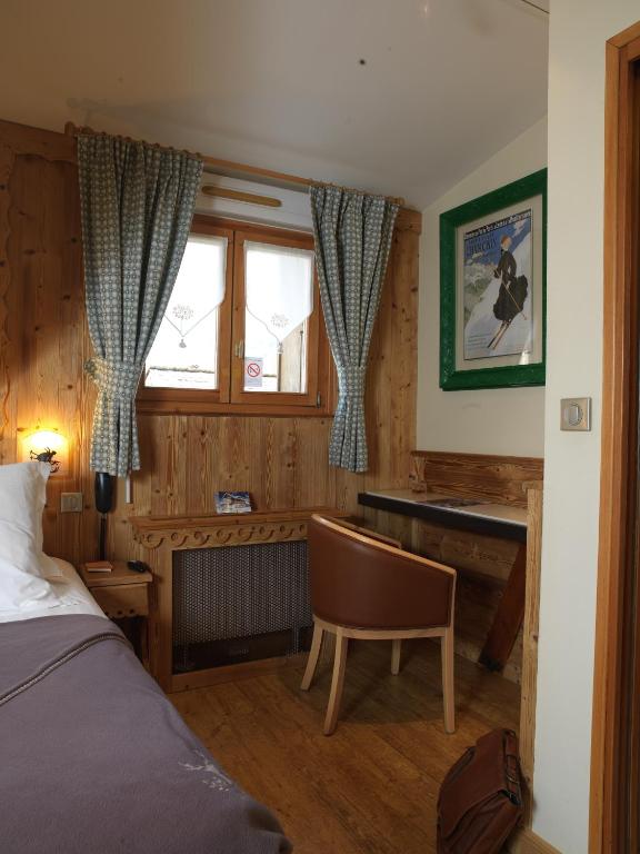 a bedroom with a bed and a desk and window at Auberge du Manoir in Chamonix