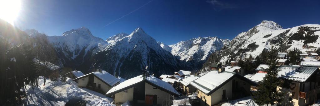 einen schneebedeckten Berg mit einem Dorf im Vordergrund in der Unterkunft Résidence Les Ancolies in Les Deux Alpes