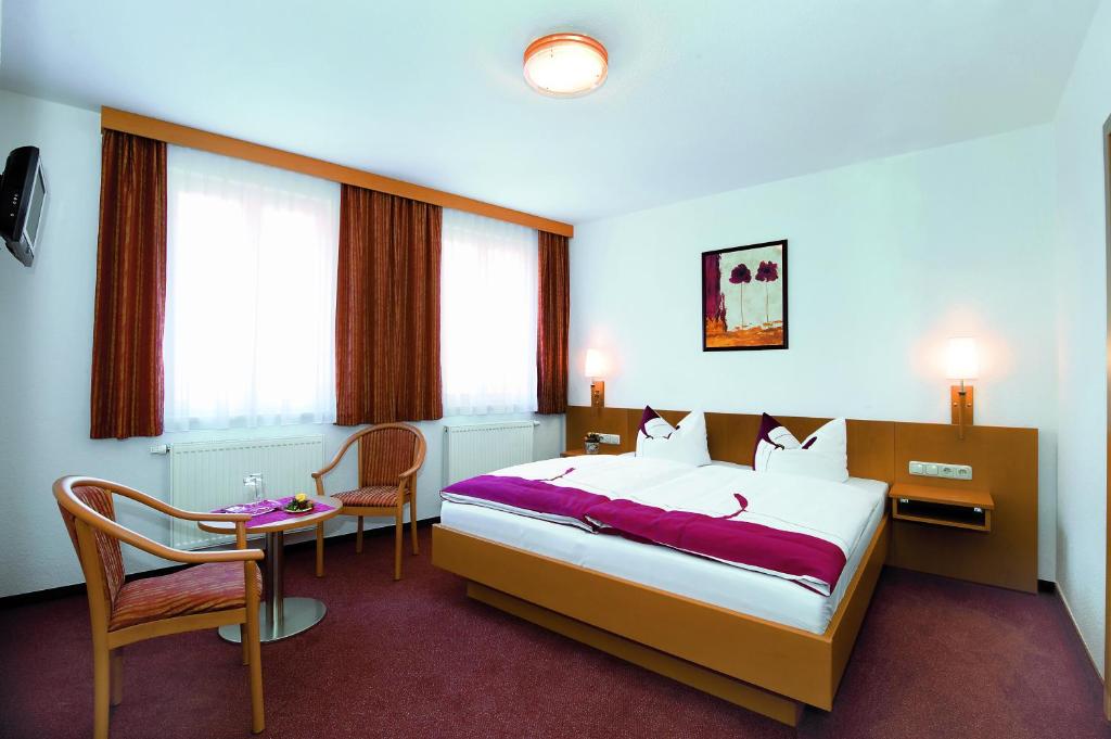 ケーニッヒスシュタイン・アン・デ・エルベにあるPension Schrägersのベッド、テーブル、椅子が備わるホテルルームです。