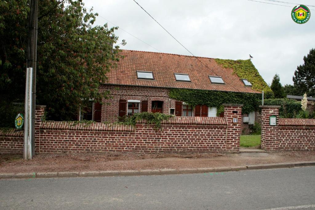 a brick house with ivy growing on the side of it at La ferme de la vallée in Auchy-au-Bois