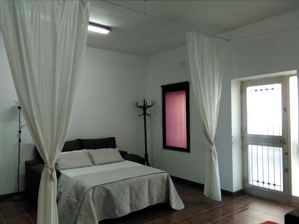 1 dormitorio con 1 cama con cortinas blancas y ventana en Ca la Valenta, en Sant Carles de la Ràpita