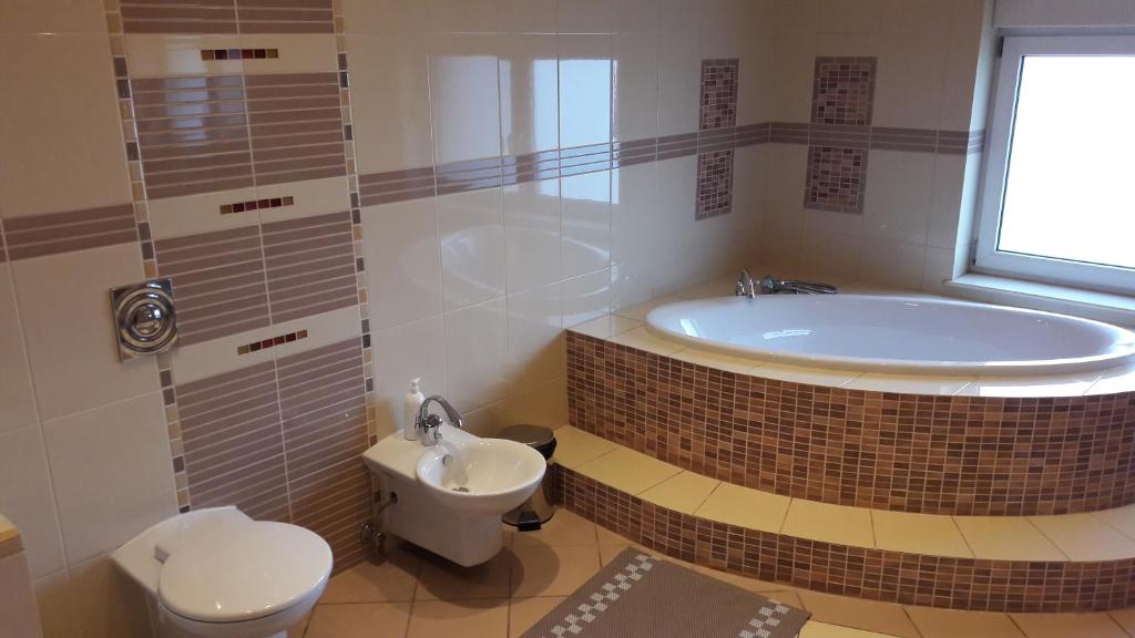 a bathroom with a tub and a toilet and a sink at Villa Paradiso in Wrocław