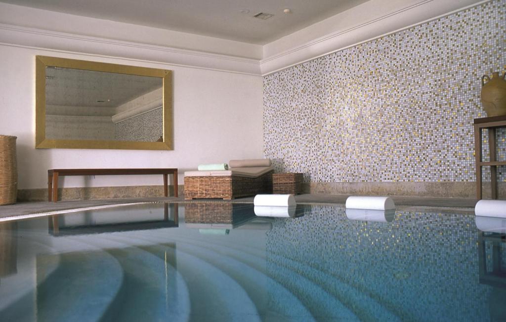a swimming pool in a room with a wall of tiles at Anassa in Polis Chrysochous