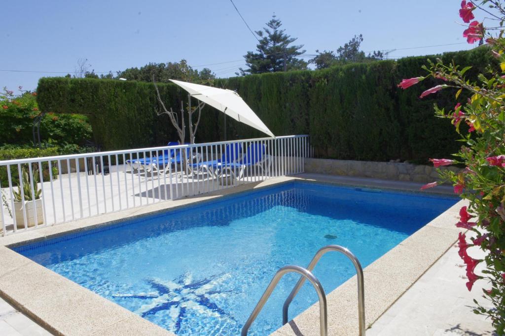uma piscina com guarda-sol e cadeiras num quintal em Ca s’Hereu em Cala Millor