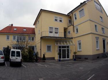 een groot geel gebouw met een wit busje geparkeerd op een parkeerplaats bij Hotel Kurpfalz in Speyer