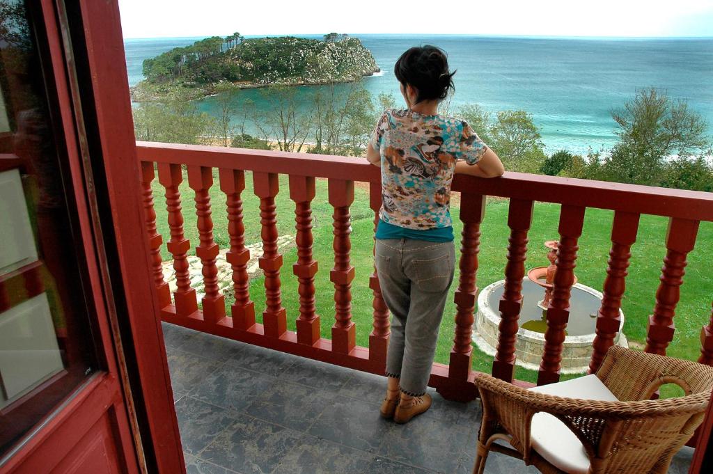 Una mujer parada en un balcón con vistas al océano en Hotel Villa Itsaso, en Lekeitio