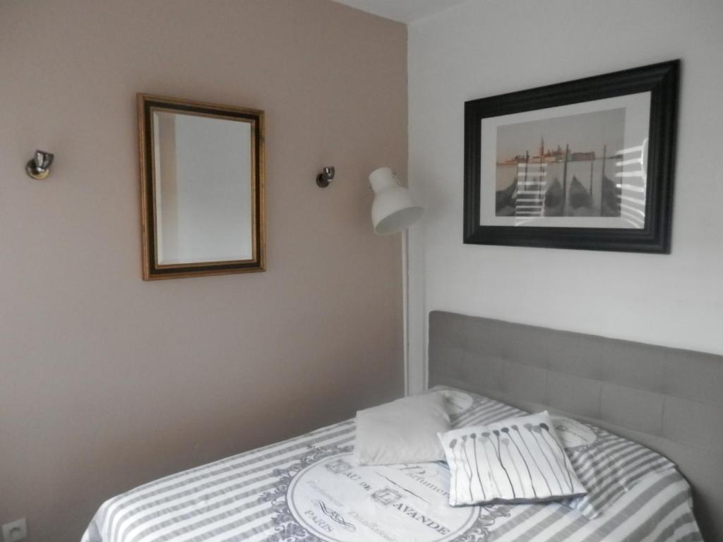 - un lit avec 2 oreillers et un miroir mural dans l'établissement Résidence Amiens hyper Centre, à Amiens