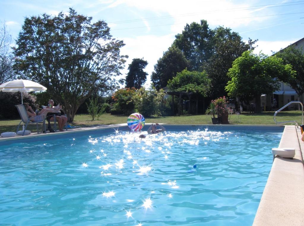 a child playing in a swimming pool with a ball at The Retreat @ Le Grand Bois in Miramont-de-Guyenne