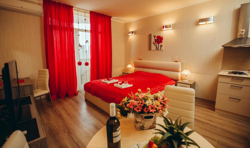 a bedroom with a red bed and a bottle of wine at Royal Apartments in Batumi