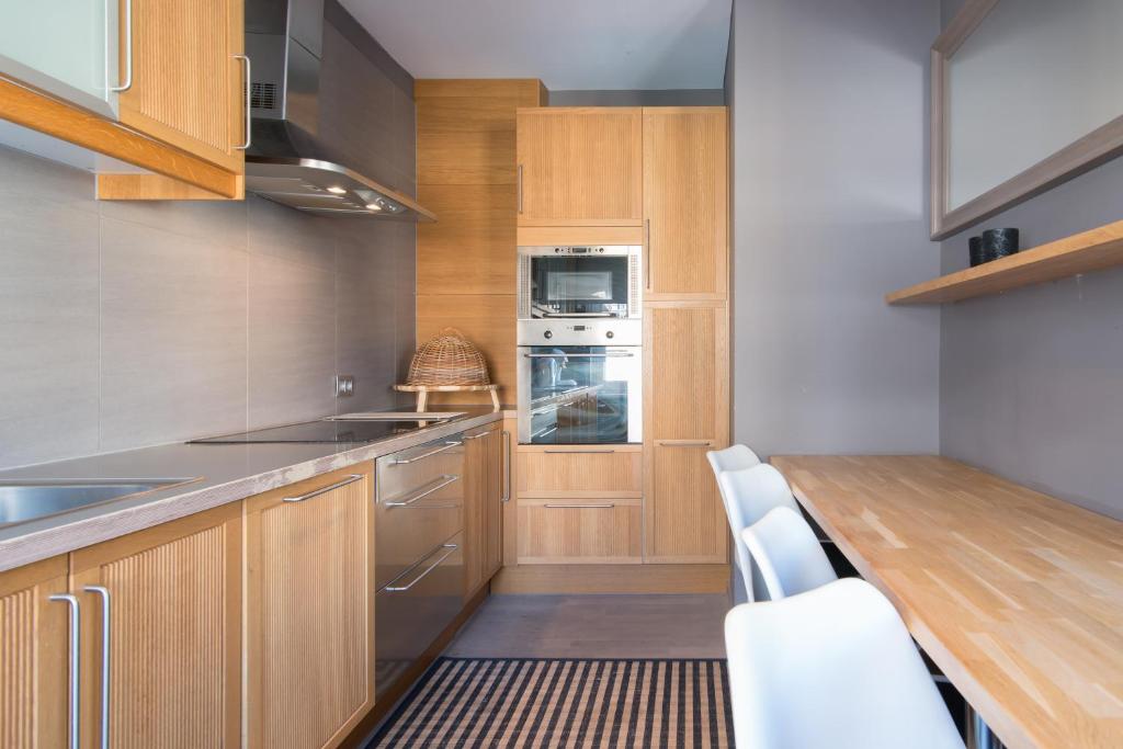 une cuisine avec des placards en bois et une table avec des chaises blanches dans l'établissement App De Panne 2, à La Panne