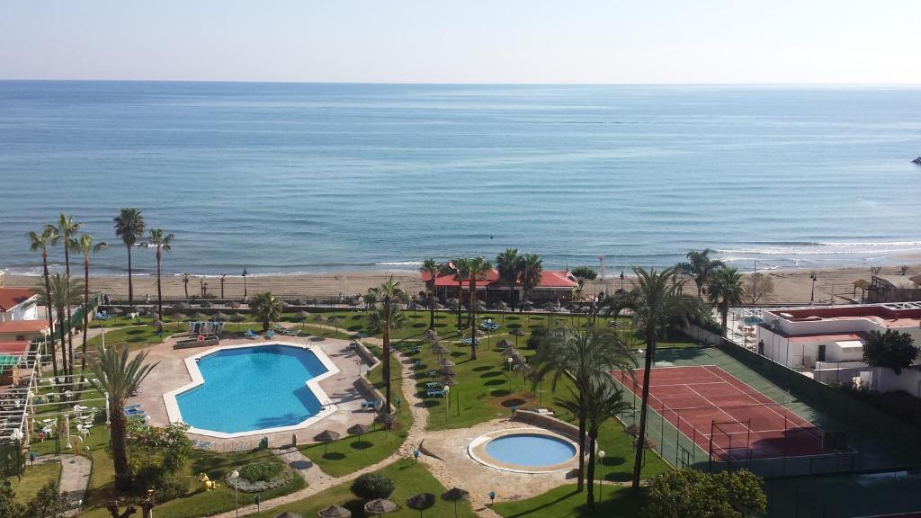 Una vista aérea de un resort con piscina y el océano. en TORREMOLINOS CARIHUELA 1ª LINEA PLAYA, en Torremolinos