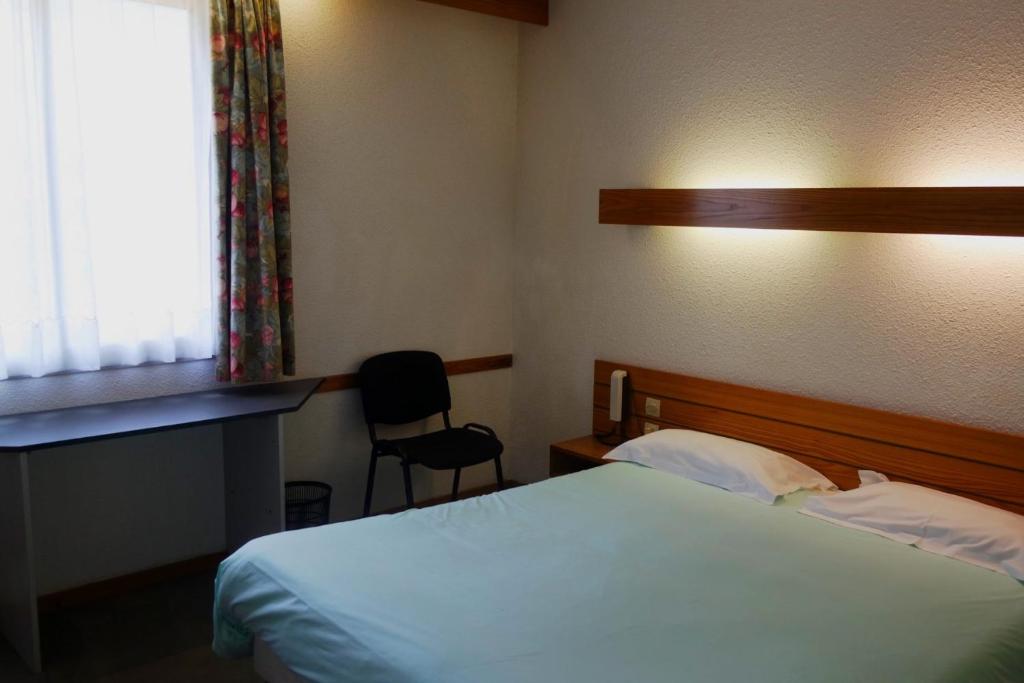 een hotelkamer met een bed en een stoel bij Appart'hôtel Le Tulipier in Cransac