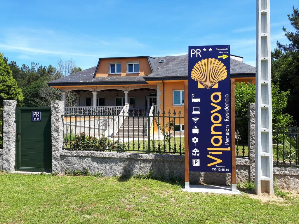 una casa con un cartello di fronte a un cancello di Pension Vilanova a Sigüeiro