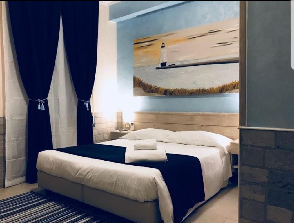 ein Schlafzimmer mit einem Bett mit einem Gemälde eines Leuchtturms in der Unterkunft Fiumicino Airport B&B Deluxe in Fiumicino