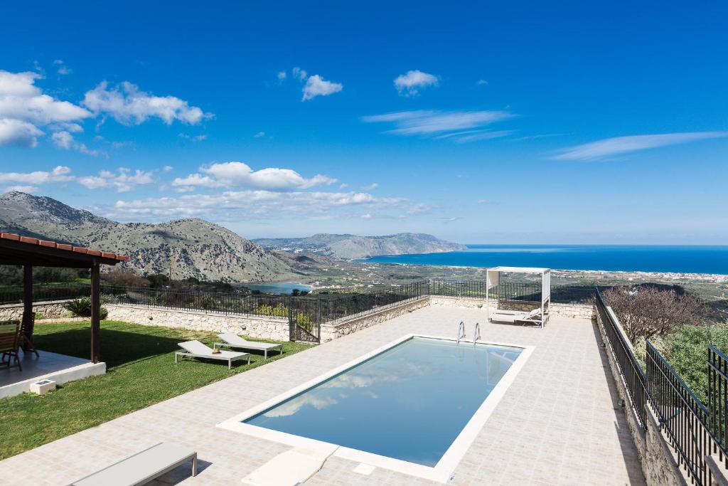 a villa with a swimming pool and a view of the ocean at Thea Villas in Kournás