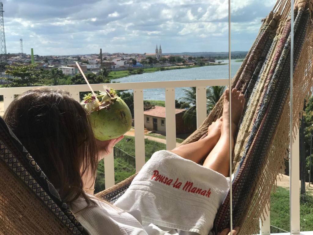 a woman sitting in a hammock with a donut in her mouth at Pousada e Restaurante Manah in Propriá