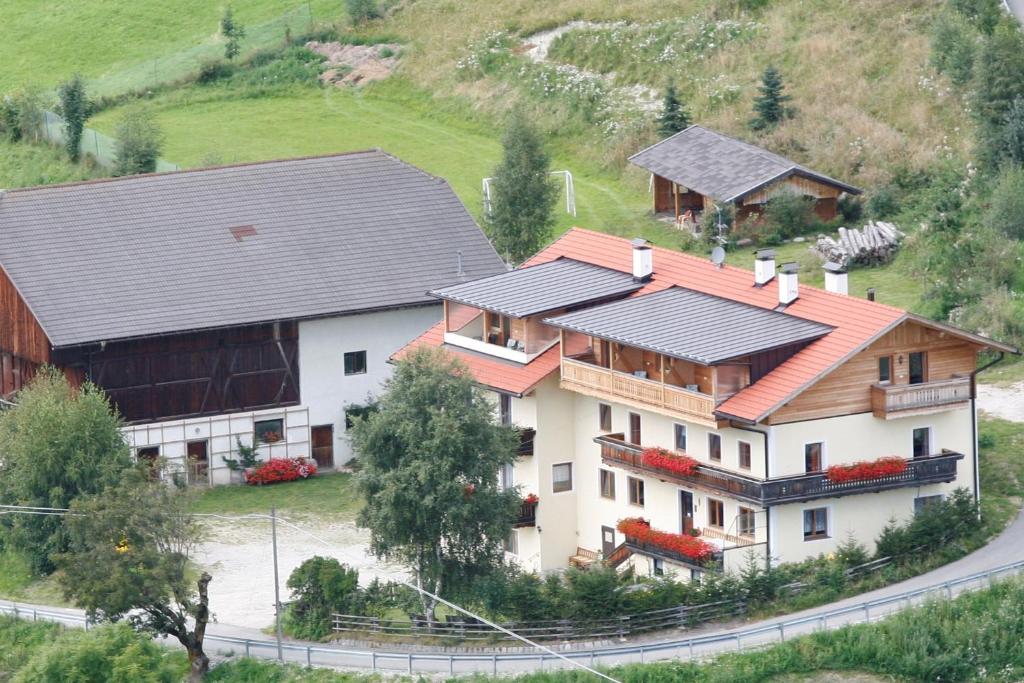 a large white house with a barn on a hill at Pension Marchnerhof in Terento