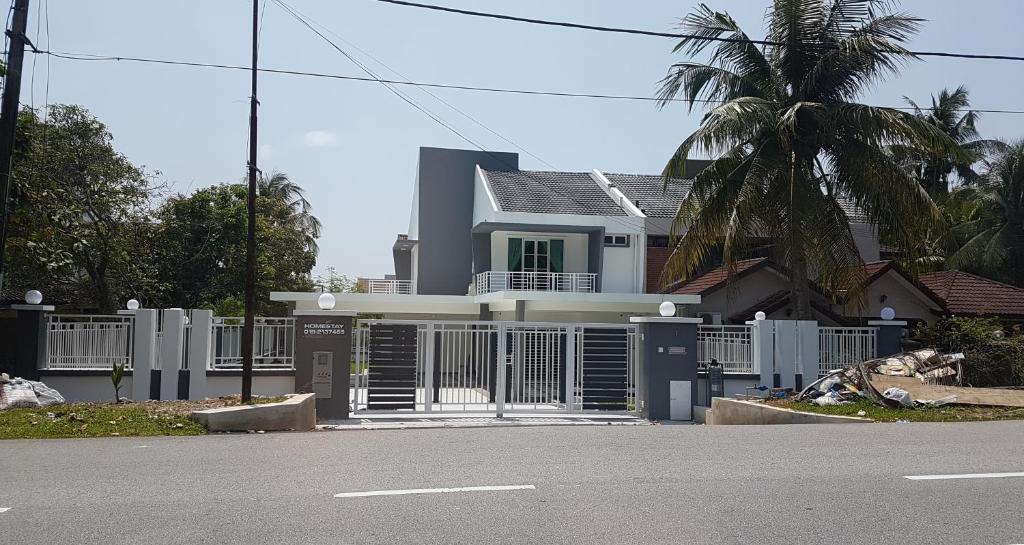 een wit huis met een poort en een palmboom bij D'Bangi Villa in Kampong Sungai Ramal Dalam