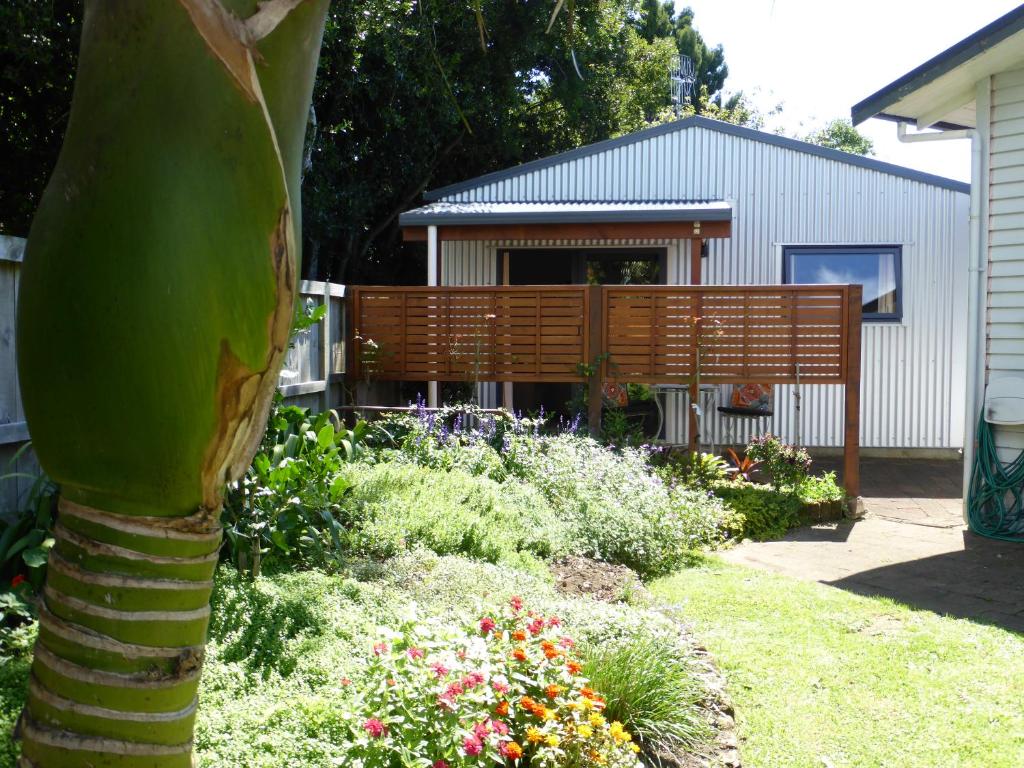 a garden with a palm tree and flowers in front of a house at Bungalow on Bell Common in Tauranga