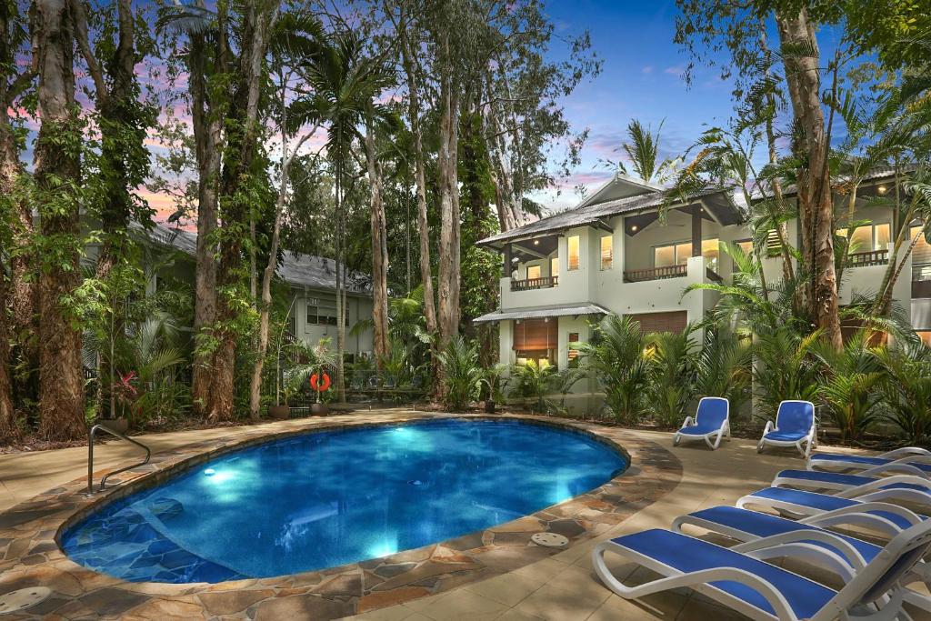 a swimming pool in front of a house with chairs at The Reef Retreat Palm Cove in Palm Cove
