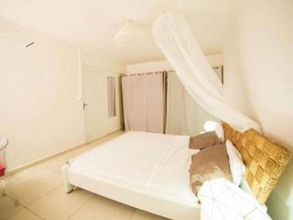 a white bed in a room with a curtain at Bounaco in Le Gosier
